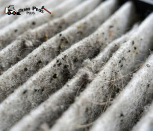 A person wearing blue nitrile gloves wiping a white countertop with a microfiber cloth and a spray bottle labeled soap solution